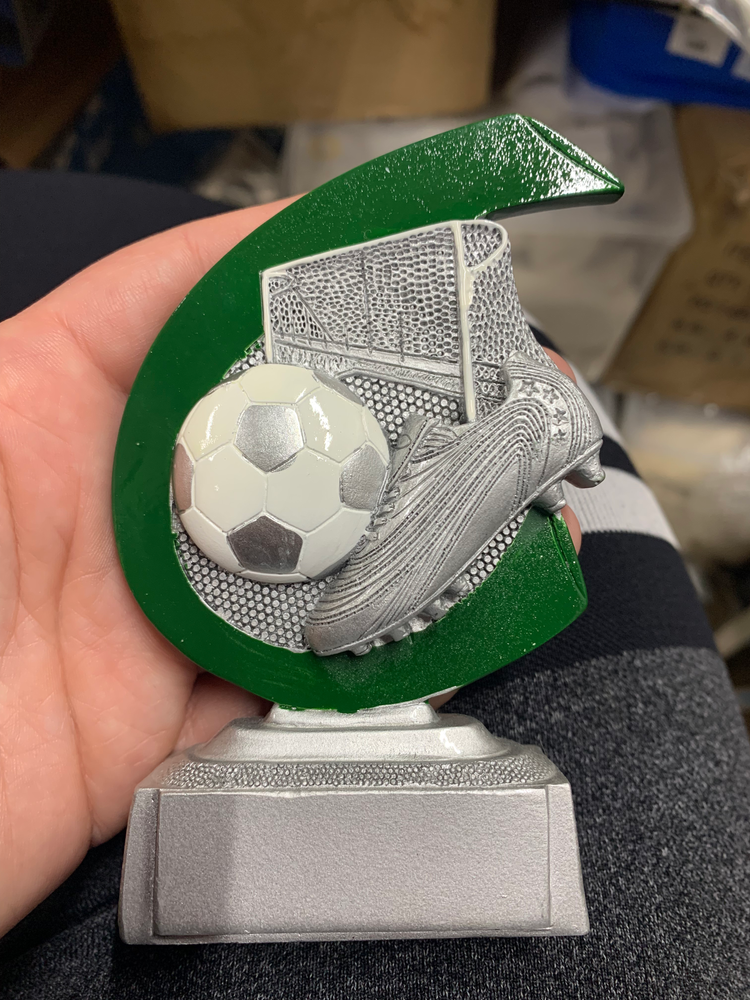 Official Simcoe listing photo of the green and silver clearance soccer trophy held in a hand